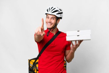 Pizza delivery man with work uniform picking up pizza boxes over isolated white background showing and lifting a finger