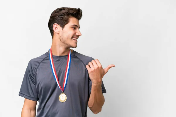 stock image Young caucasian man with medals over isolated white background pointing to the side to present a product