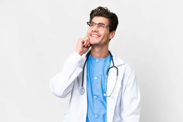 Junger Arzt Vor Isoliertem Weißen Hintergrund Denkt Beim Nachschlagen Eine — Stockfoto