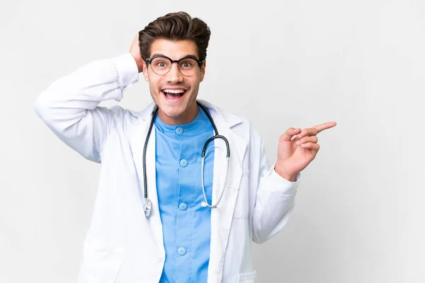 Mladý Lékař Muž Přes Izolované Bílé Pozadí Překvapen Ukazuje Prstem — Stock fotografie
