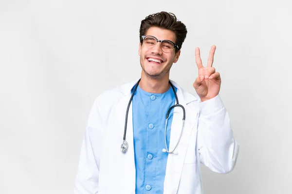 Молодий Лікар Над Ізольованим Білим Тлом Посміхається Показує Знак Перемоги — стокове фото