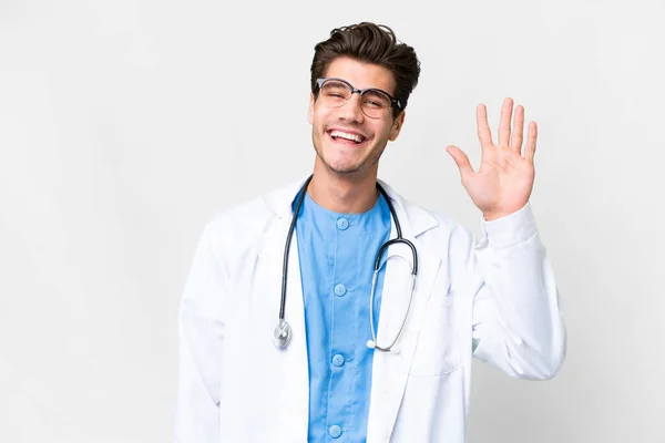 Νεαρός Γιατρός Άνθρωπος Πάνω Από Απομονωμένο Λευκό Φόντο Χαιρετισμό Χέρι — Φωτογραφία Αρχείου