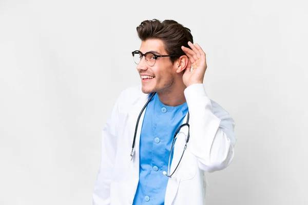Junger Arzt Vor Isoliertem Weißen Hintergrund Hört Etwas Indem Die — Stockfoto