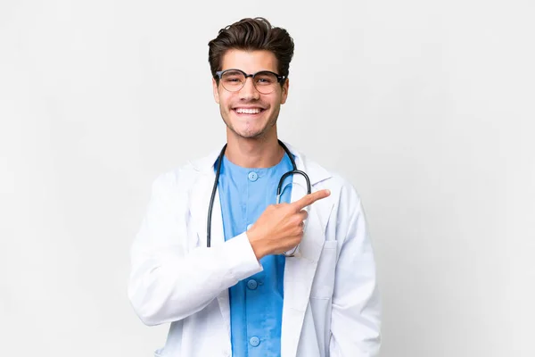 Mladý Lékař Muž Přes Izolované Bílé Pozadí Ukazuje Straně Prezentovat — Stock fotografie