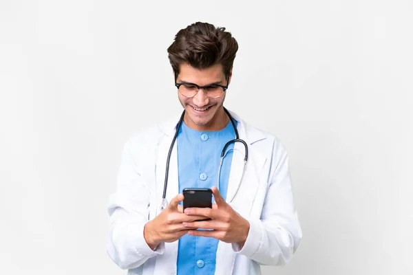Молодий Лікар Над Ізольованим Білим Тлом Надсилає Повідомлення Мобільним Телефоном — стокове фото