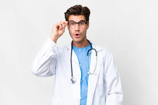 Jovem Médico Homem Sobre Isolado Fundo Branco Com Óculos Surpreso — Fotografia de Stock