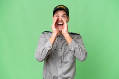 Arka planda kalan genç güvenlik görevlisi bağırıyor ve bir şey duyuruyor.