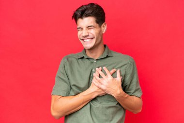 Beyaz tenli yakışıklı adam kırmızı arka planda izole edilmiş, kalbinde bir ağrı var.