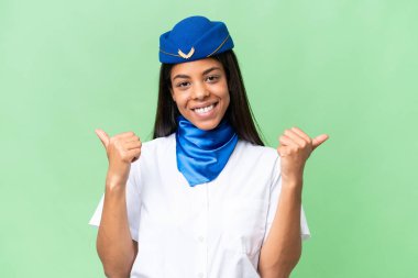 Uçak hostesi Afro-Amerikan kadın izole edilmiş arka planda başparmakları havada ve gülümsüyor.