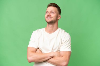 Sarışın, beyaz, soyutlanmış bir adam gülümserken yukarı bakıyor.