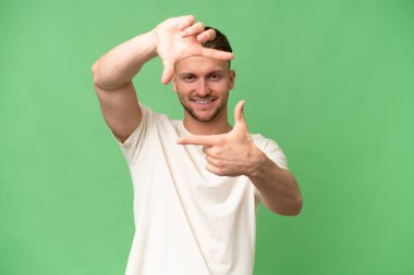 İzole edilmiş, odaklanmış yüzü olan genç, sarışın, beyaz bir adam. Çerçeve sembolü