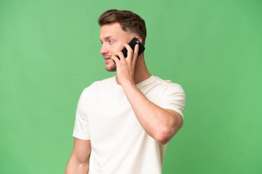 Sarışın, beyaz, soyutlanmış bir geçmişi olan bir adam cep telefonuyla sohbet ediyor.