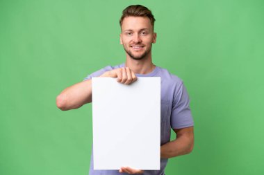 Sarışın, beyaz bir adam izole edilmiş bir arka planda elinde mutlu bir ifadeyle boş bir levha tutuyor.