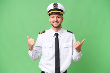 Uçak pilotu izole edilmiş arka planda, baş parmak hareketleriyle ve gülümsemesiyle.