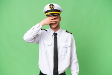 Uçak pilotu izole edilmiş arka planda, gözleri kapalı ve gülümsüyor.