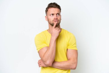 Beyaz arka planda izole edilmiş genç sarışın bir adam yukarı bakarken şüpheleri var.