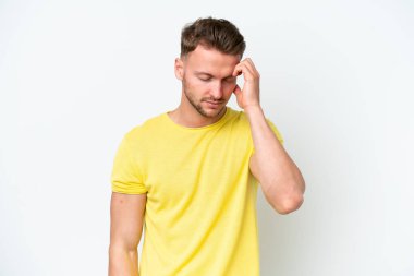 Beyaz arka planda başı ağrıyan genç, sarışın, beyaz bir adam.