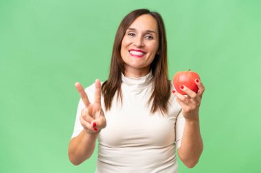 Stüdyonun arka planında elma tutan orta yaşlı kadın. 