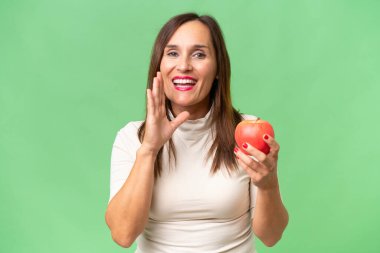 Stüdyonun arka planında elma tutan orta yaşlı kadın. 