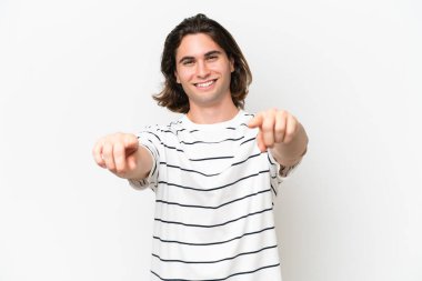 Beyaz arka planda izole edilmiş genç yakışıklı adam mutlu bir ifadeyle öne bakıyor.