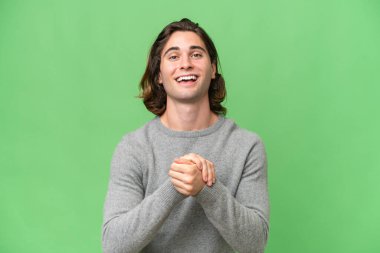Yeşil krom arka planda izole genç beyaz adam gülüyor.