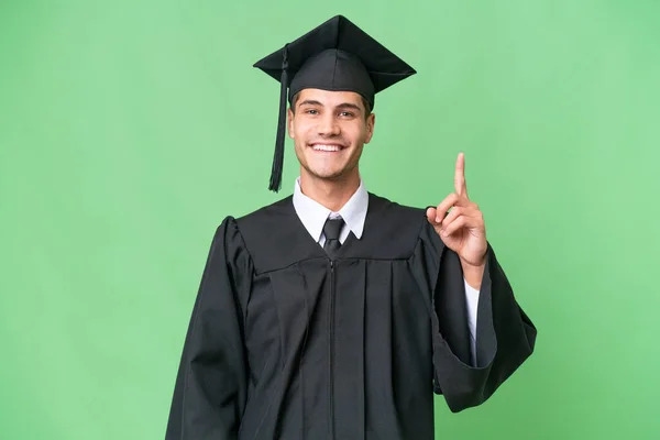 Νεαρός Απόφοιτος Πανεπιστημίου Καυκάσιος Άνδρας Πάνω Από Απομονωμένη Φόντο Δείχνει — Φωτογραφία Αρχείου