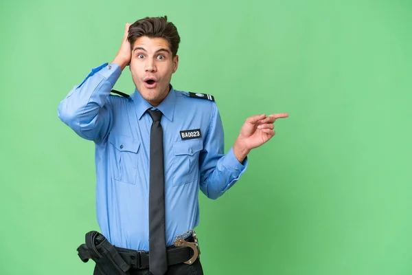 Молодий Поліцейський Над Ізольованим Тлом Здивований Вказує Пальцем Бік — стокове фото