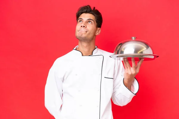 Jeune Chef Caucasien Homme Tenant Plateau Isolé Sur Fond Rouge — Photo