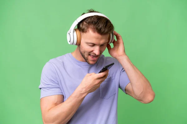 Joven Rubia Caucásica Hombre Sobre Aislado Fondo Escuchando Música Con — Foto de Stock