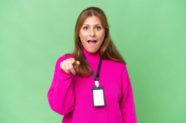 Kimliği izole edilmiş orta yaşlı beyaz kadın şaşırmış ve ön tarafı işaret ediyor.