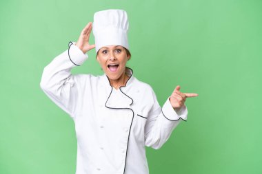 Orta yaşlı aşçı kadın, izole edilmiş arka planda şaşkın şaşkın geziyor.