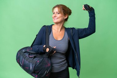 Spor çantalı orta yaşlı bir kadın izole edilmiş arka planda güçlü bir jest yapıyor.