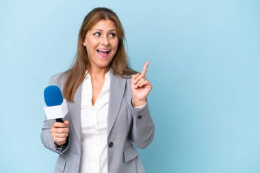 Orta yaşlı televizyon sunucusu kadın, mavi arka planda tek parmağını kaldırarak çözümü bulmaya çalışıyor.