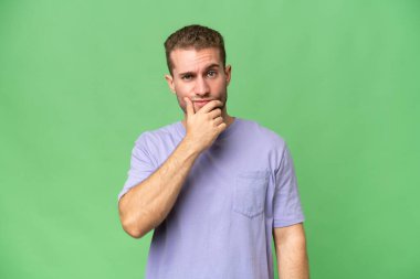 Yeşil krom arka planda izole edilmiş yakışıklı, beyaz bir adam. Şüpheleri var.