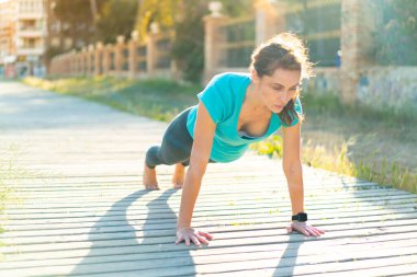 Dışarıda yoga yapan genç bir kadın.
