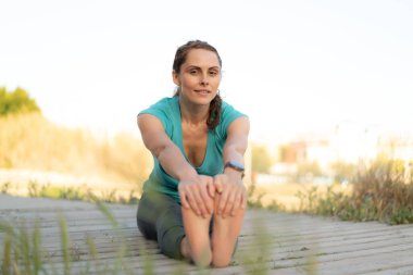 Dışarıda yoga yapan genç bir kadın.