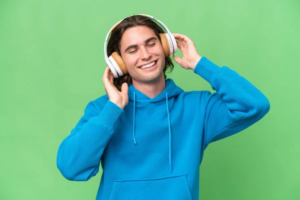 Joven Hombre Guapo Aislado Fondo Croma Verde Escuchando Música Cantando —  Fotos de Stock