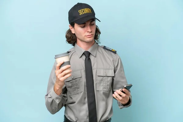 Giovane Uomo Salvaguardia Isolato Sfondo Blu Con Caffè Portare Cellulare — Foto Stock