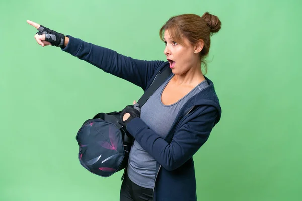 中年スポーツ女性とともにスポーツバッグ上の隔離された背景を指す — ストック写真