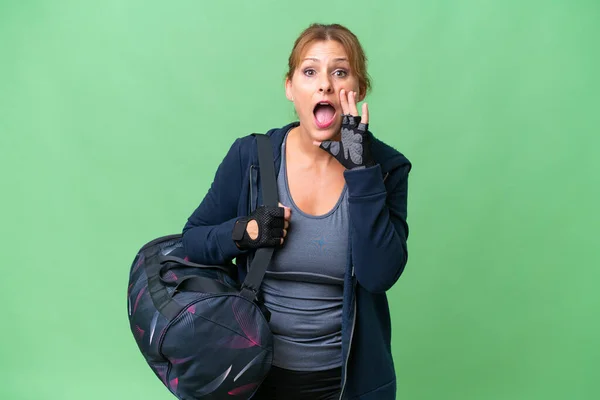 中年スポーツ女性とともにスポーツバッグ上の隔離された背景叫びとともに口全体オープン — ストック写真