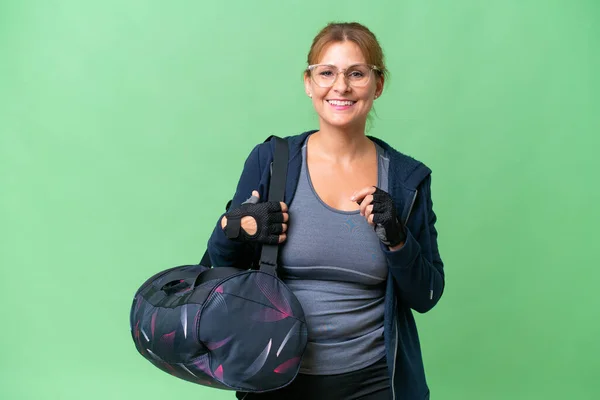 stock image Middle-aged sport woman with sport bag over isolated background with glasses and happy