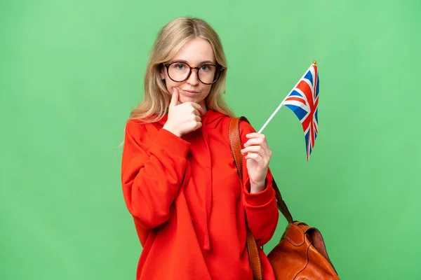 年轻的惊慌失措的女人举着英国国旗 有着孤立的背景思维 — 图库照片
