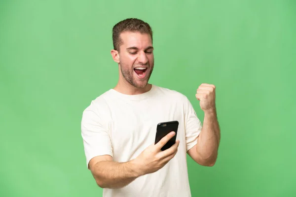 Young Handsome Caucasian Man Isolated Green Chroma Background Phone Victory — Stock Photo, Image