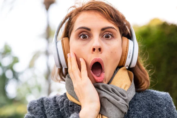 Brunette Vrouw Luisteren Muziek Met Koptelefoon Buitenlucht Verrast Geschokt Terwijl — Stockfoto