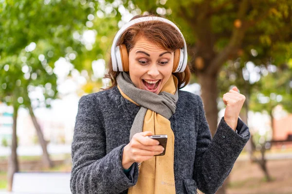 Bruneta Žena Poslouchá Hudbu Sluchátky Venku Překvapen Posílá Zprávu — Stock fotografie