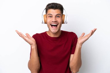 Beyaz arka planda izole genç beyaz adam şaşırdı ve müzik dinliyor