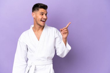Mor arka planda karate yapan genç beyaz adam çözümü bulmak için parmağını kaldırıyor.