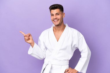 Mor arka planda karate yapan genç, beyaz bir adam parmak işareti yapıyor.