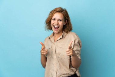 Genç Gürcü kadın, mavi arka planda izole edilmiş, cepheye bakıyor ve gülümsüyor.