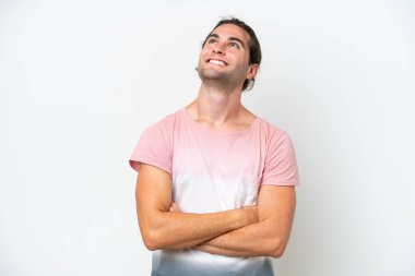 Beyaz arka planda beyaz tenli yakışıklı adam gülümserken yukarı bakıyor.